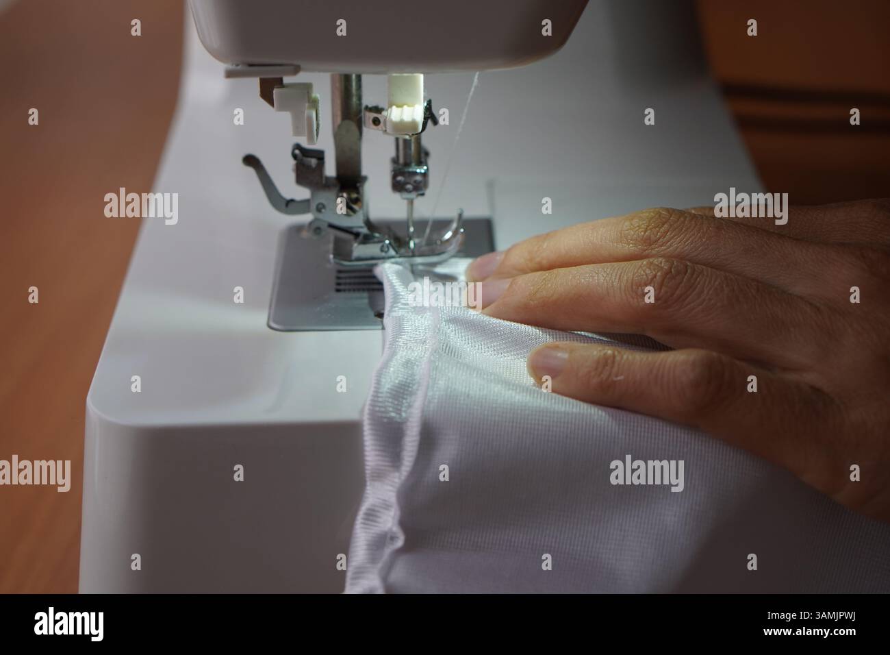les petites entreprises. gros plan de la machine à coudre avec les mains d'une femme plaçant le tissu spunbond. Banque D'Images