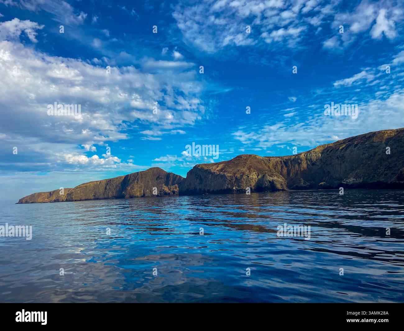 Les eaux calmes reflètent le ciel bleu et les falaises escarpées le long du littoral. - Image de stock capturée avec un smartphone