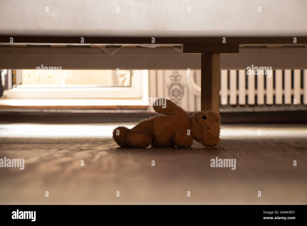 Bébé ours en peluche brun abandonné repose sous le lit dans la chambre à coucher à la maison, ours en peluche sous le lit Banque D'Images