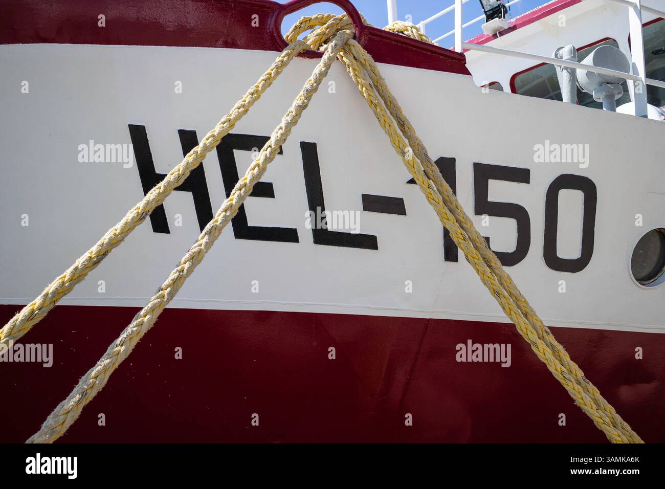 Un bateau rouge et blanc avec le numéro 150 dessus. Le bateau est attaché à un quai Banque D'Images