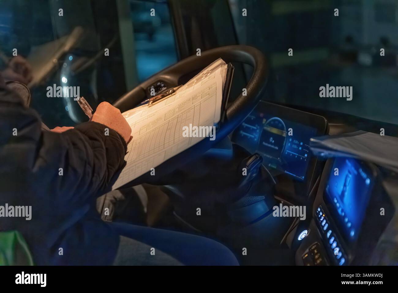 Le conducteur vérifie les documents de travail dans l'éclairage nocturne de la cabine une fois le voyage terminé. Toutes les marques de commerce potentielles sont supprimées. Horizontalement. Banque D'Images