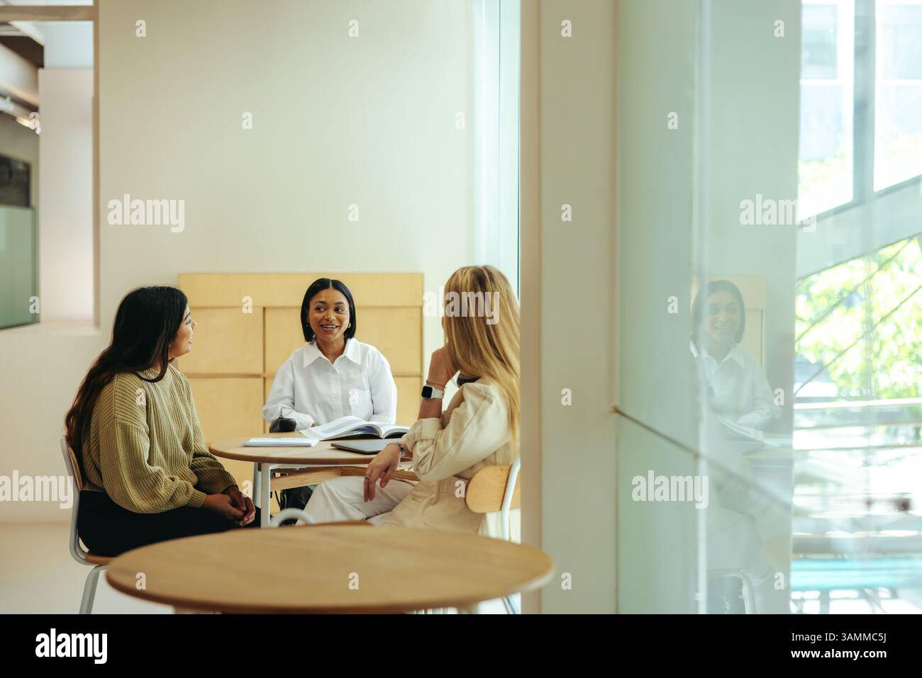 Les élèves se réunissent dans un café urbain pour une discussion collaborative, mettant l'accent sur le travail d'équipe et la connexion dans un environnement académique. Banque D'Images