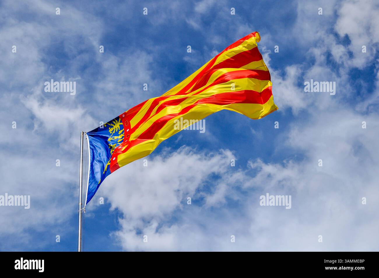 Drapeau régional de Valence en mouvement avec une composition dynamique et des couleurs vives contre le ciel blu partialy, symbolisant la culture, le nationalisme et le patrimoine. Banque D'Images