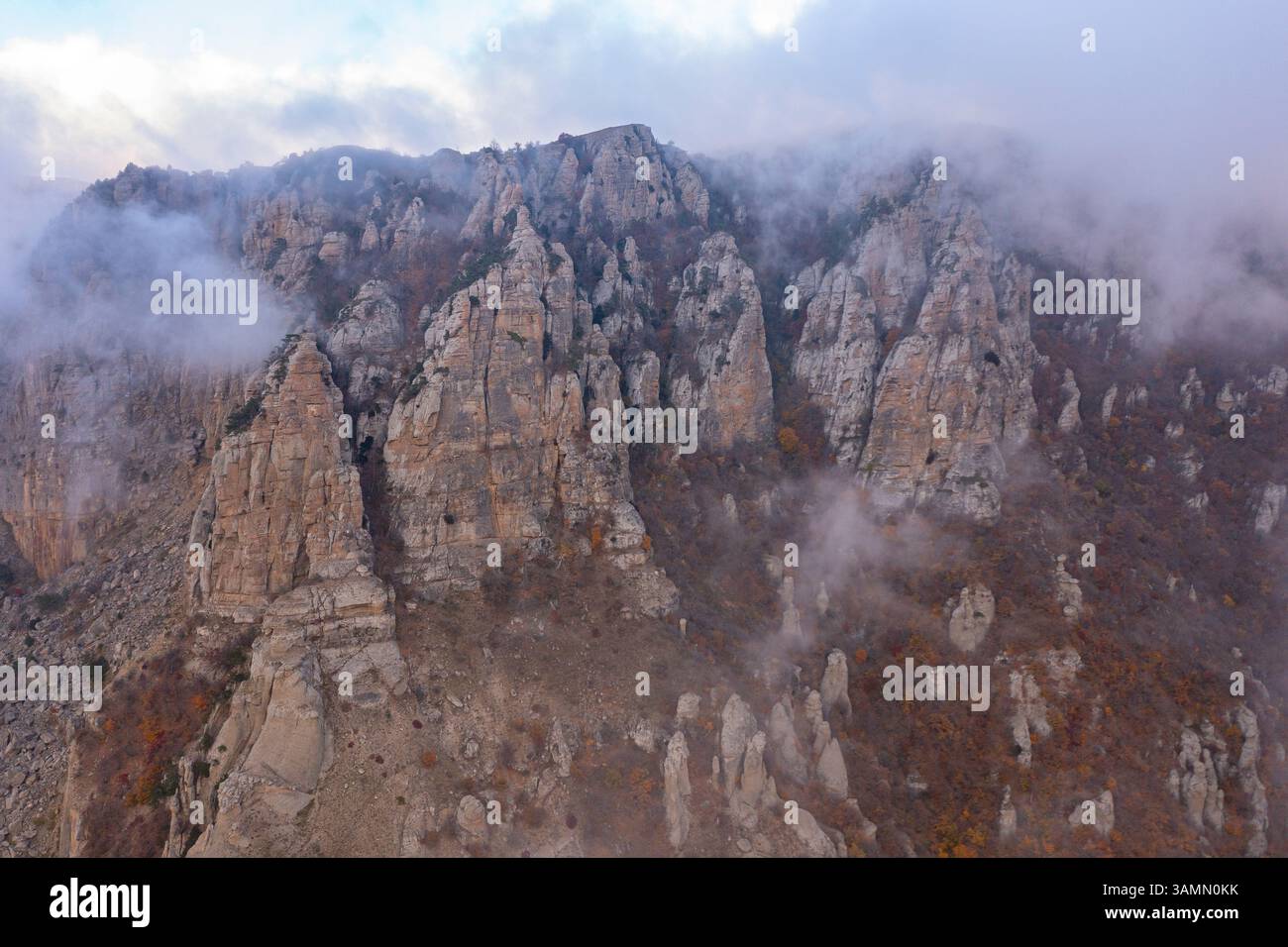 Vue aérienne d'un paysage montagneux avec des nuages bas et du brouillard au coucher du soleil dans la région de Crimée, République autonome de Crimée, Ukraine. Banque D'Images