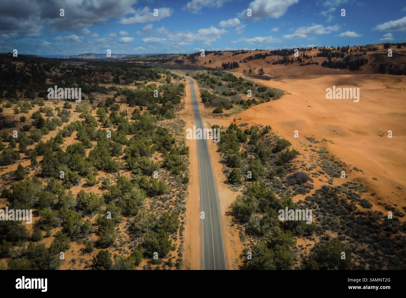 Vue aérienne des dunes de sable rose corail avec une route sinueuse et une végétation clairsemée, Utah, États-Unis. Banque D'Images