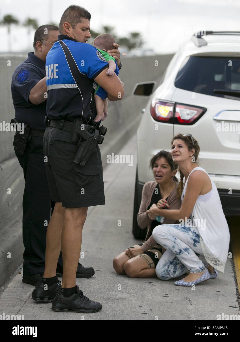 20 février 2014 - Miami, FL, États-Unis - Sweetwater, Fla., L'officier Amauris Bastidas aide au sauvetage du petit garçon de 5 mois, Sebastian de la Cruz, qui a cessé de respirer. Au centre, la tante du bébé, Pamela Rauseo, 37 ans, a effectué une RCP après avoir tiré son VUS sur le côté de la route le long de la route 836 de Floride, juste à l'est de la 57e Avenue, le jeudi 20 février 2014. À droite se trouve Lucila Godoy, qui a arrêté sa voiture pour aider au sauvetage. (Crédit image : © Al Diaz/MCT/ZUMAPRESS.com) Banque D'Images