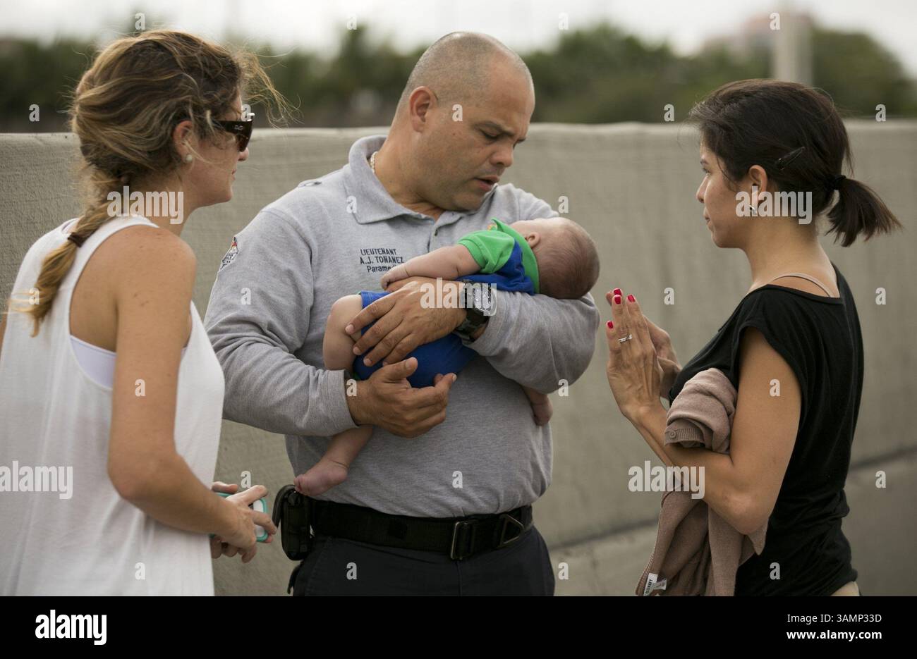 20 février 2014 - Miami, FL, États-Unis - le lieutenant paramédical des pompiers de Miami-Dade, Alvaro Tonanez, aide à sauver Sebastian de la Cruz, 5 mois, qui a cessé de respirer. À droite, la tante du bébé, Pamela Rauseo, a effectué une RCP après avoir arrêté son VUS sur le côté de la route le long de la route 836 de l'État de Floride, juste à l'est de la 57e Avenue, autour du jeudi 20 février 2014. À gauche se trouve Lucila Godoy, qui a arrêté sa voiture pour aider à la RCP. (Crédit image : © Al Diaz/MCT/ZUMAPRESS.com) Banque D'Images