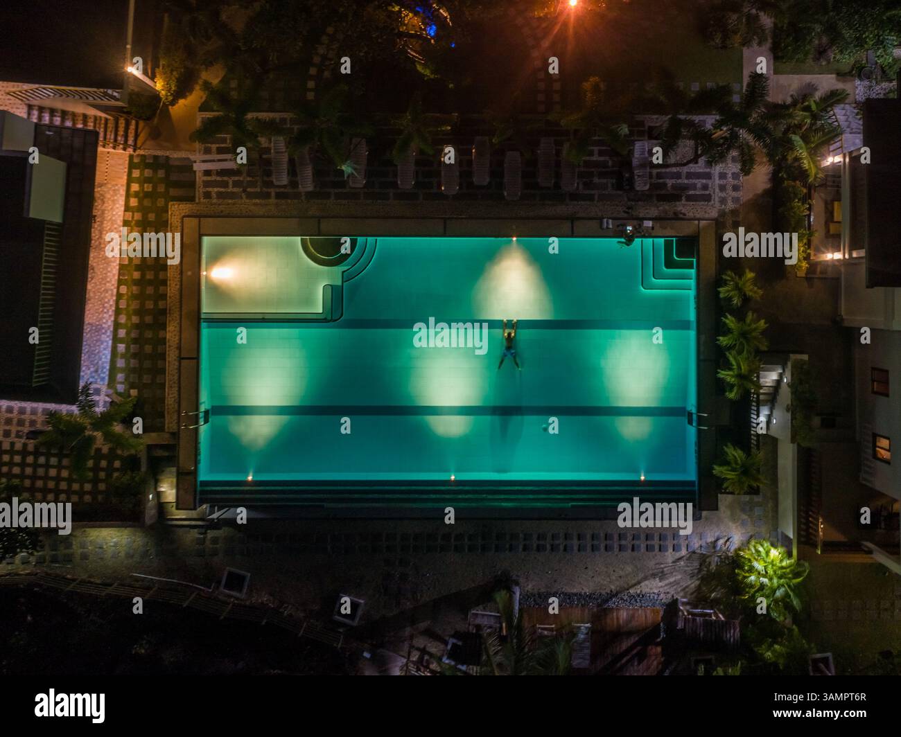 Vue aérienne de nuit de la piscine illuminée et de la natation de l'homme, Tagbilaran, Philippines. Banque D'Images