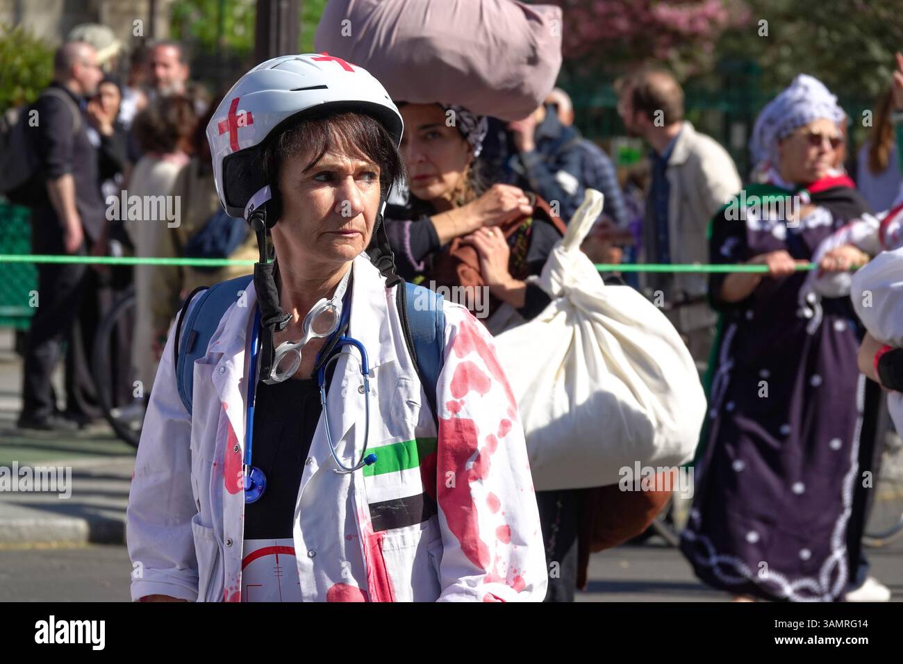 Costume de travailleur médical taché de sang lors d’une manifestation pro-palestinienne à Paris, symbolisant les attaques contre l’aide humanitaire de Gaza. Urgence, scène émotionnelle avec dem Banque D'Images
