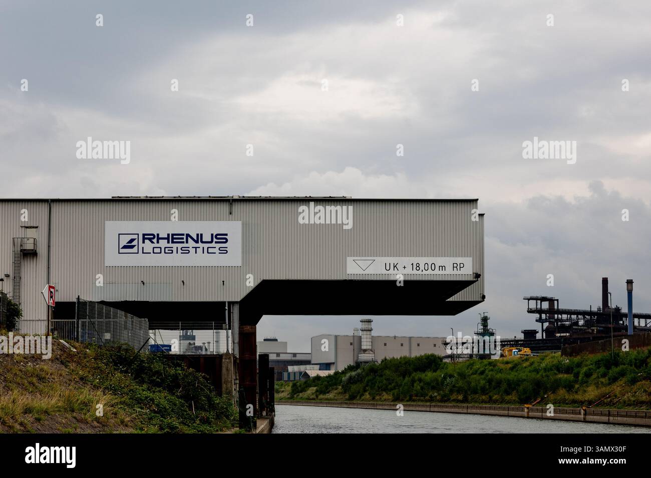 Duisburg, Allemagne - 27 juillet 2024 : un centre logistique Rhenus est vu à côté d'un canal, avec un ciel gris au-dessus. L'emplacement indique un industriel Banque D'Images