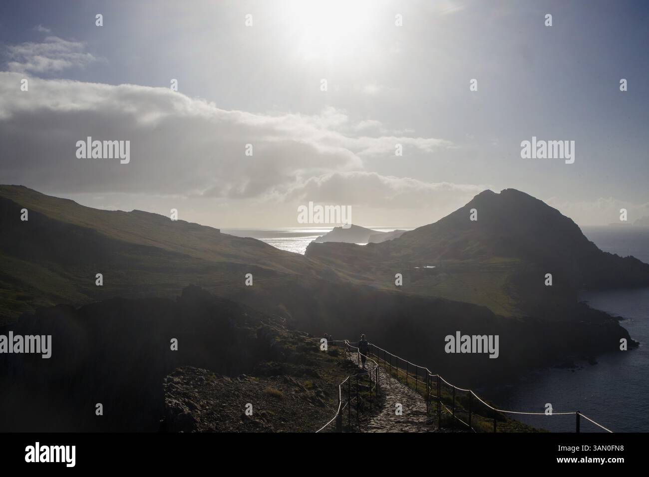 Un randonneur marche le long d'un chemin sinueux à Ponta de Sao Lourenco à Madère, entouré de falaises à couper le souffle et de l'océan Atlantique étincelant sous une bri Banque D'Images