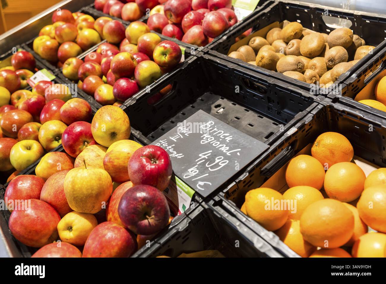 Comptoir de fruits dans un supermarché ou un magasin d'alimentation biologique, ici avec différents types de pommes, kiwis, oranges et un compartiment vide pour les poires Banque D'Images