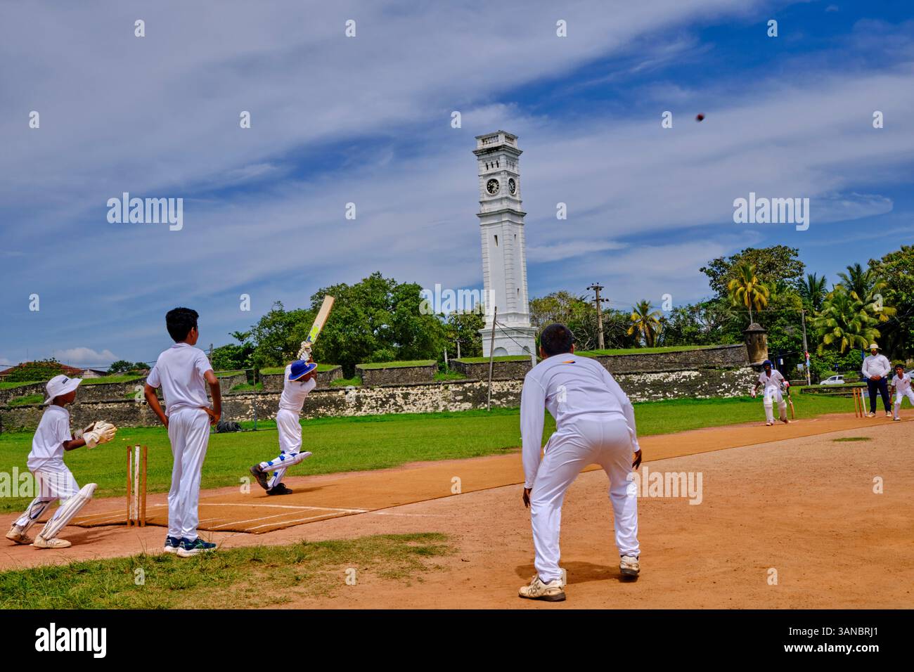 Sri Lanka, Province du Sud, district de Matara, Matara, enfants jouant au cricket devant la tour de l'horloge du Fort de Matara Banque D'Images