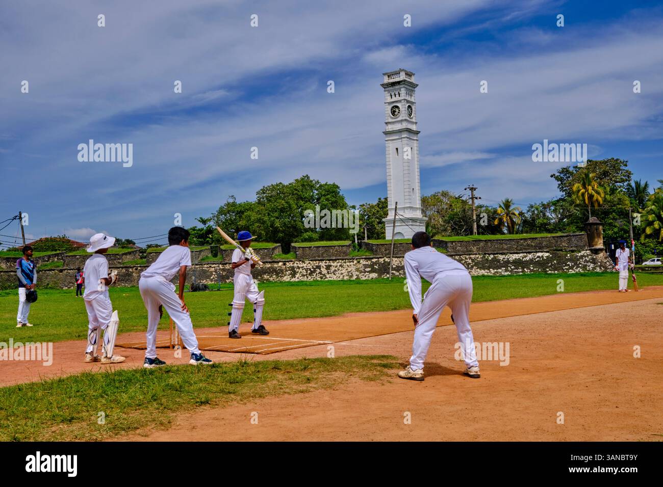 Sri Lanka, Province du Sud, district de Matara, Matara, enfants jouant au cricket devant la tour de l'horloge du Fort de Matara Banque D'Images