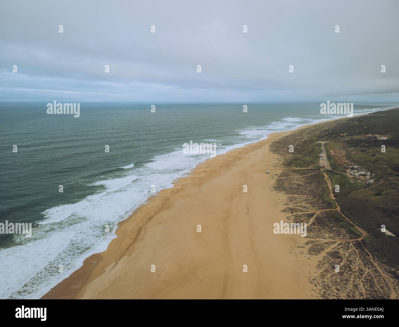 Vue aérienne de la plage de Praia do Norte avec belle côte de sable et vagues de l'océan sereines, Nazare, Leiria, Portugal. Banque D'Images