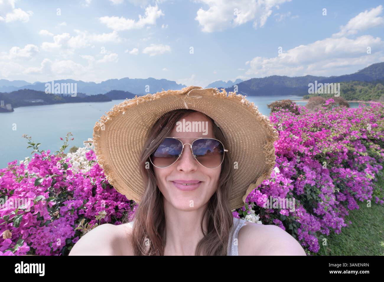 Portrait d'une voyageuse en lunettes de soleil et un chapeau de paille prenant des selfies dans le contexte de la nature thaïlandaise, le lac Cheo LAN dans le parc Khao Sok. Banque D'Images