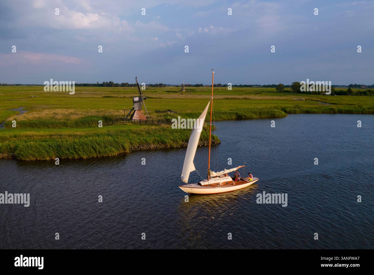 Vue aérienne du coucher de soleil serein sur de ALDE Feanen avec des bateaux à voile et un moulin à vent, Earnewald, Frise, pays-Bas. Banque D'Images