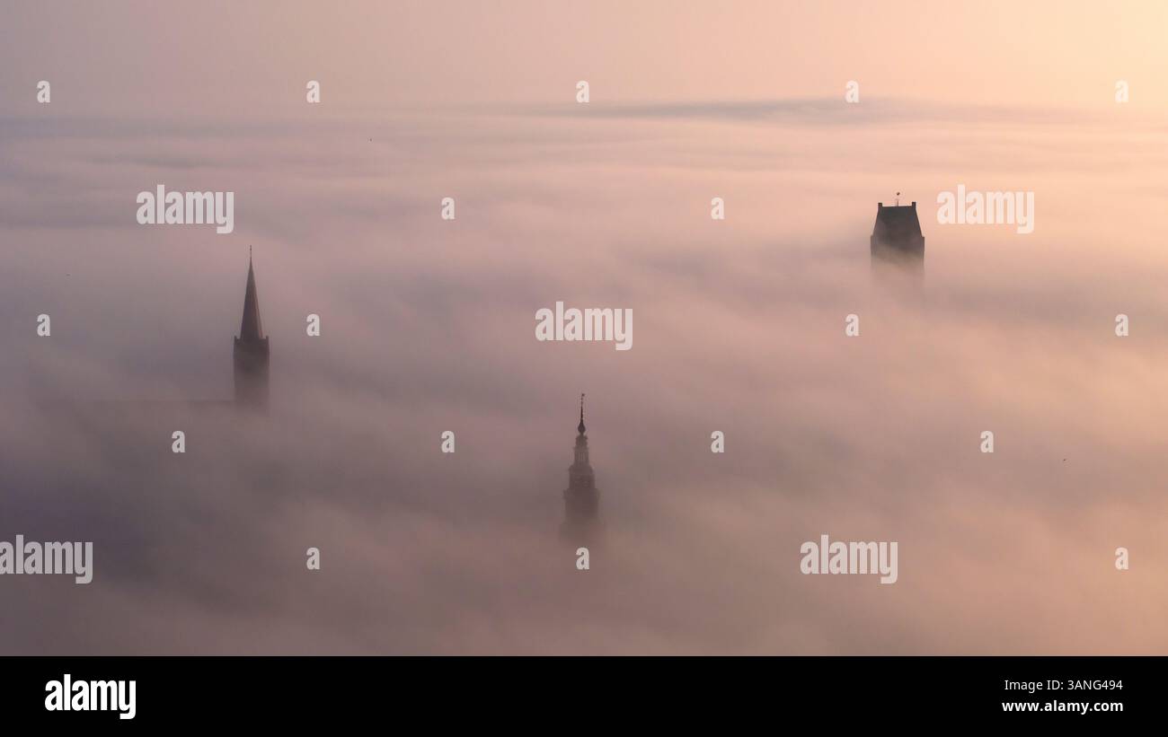Vue aérienne de l'église Martinikerk entourée de brouillard au lever du soleil, Bolsward, pays-Bas. Banque D'Images