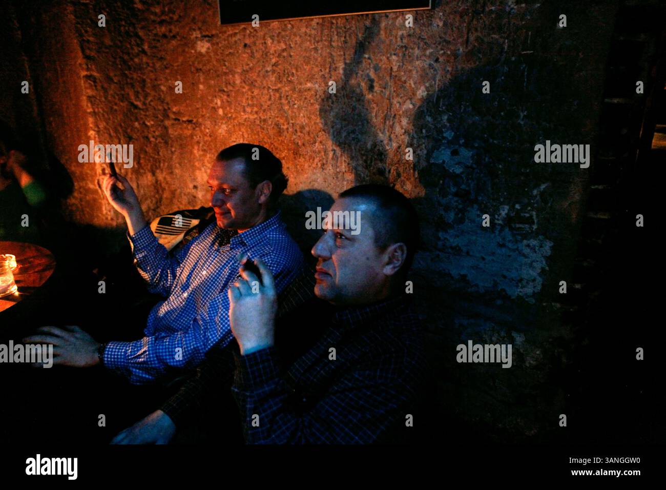 Feb 25, 2010 - Cracovie, Pologne - les touristes fument des cigares au populaire pub Alchemia dans le centre du quartier de Kazimerz. Avant la chute du communisme en Pologne, l’ancien quartier juif de Kazimerz à Cracovie était délabré et dangereux à visiter la nuit. Aujourd'hui, la région attire des milliers de touristes par an du monde entier. Le quartier était autrefois un centre animé de la vie juive avant d'être anéanti pendant la seconde Guerre mondiale. Les restaurants et cafés à thème juif servent une cuisine traditionnelle juive et polonaise et les synagogues restaurées contiennent des expositions détaillant la vie juive d'avant-guerre en Pologne. Un certain con Banque D'Images