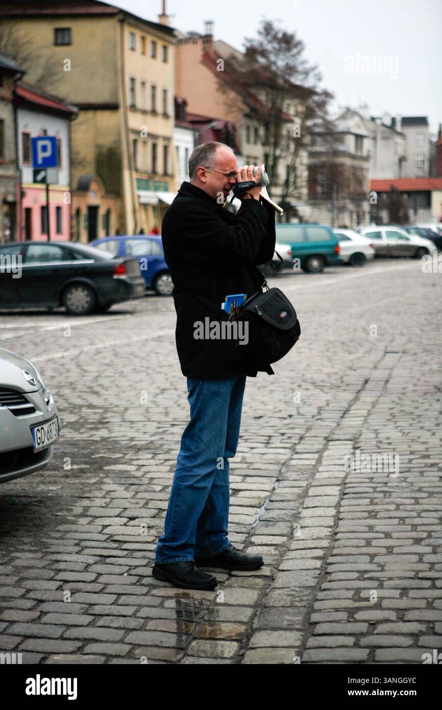27 février 2010 - Cracovie, Pologne - Un touriste à Kazimerz. Avant la chute du communisme en Pologne, l’ancien quartier juif de Kazimerz à Cracovie était délabré et dangereux à visiter la nuit. Aujourd'hui, la région attire des milliers de touristes par an du monde entier. Le quartier était autrefois un centre animé de la vie juive avant d'être anéanti pendant la seconde Guerre mondiale. Les restaurants et cafés à thème juif servent une cuisine traditionnelle juive et polonaise et les synagogues restaurées contiennent des expositions détaillant la vie juive d'avant-guerre en Pologne. Une certaine controverse existe sur les peintures antisémites et les boiseries dans quelques g. Banque D'Images