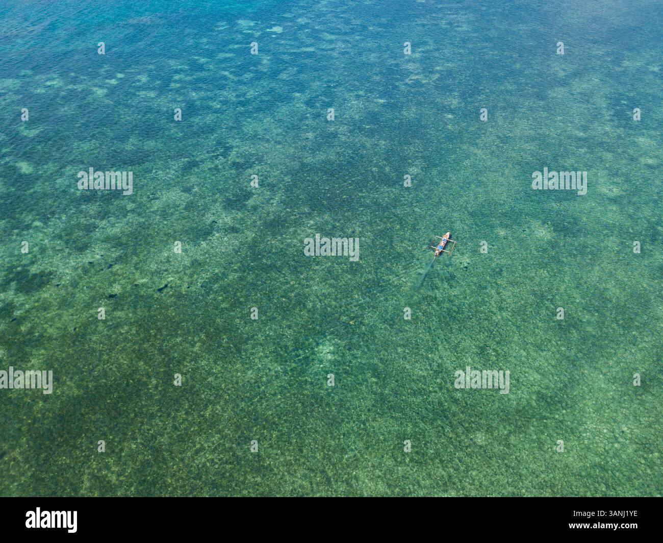 Vue aérienne d'un bateau pirogue sur des eaux cristallines entourées de récifs coralliens à Beloi, île d'Atauro, Dili, Timor-Leste Banque D'Images