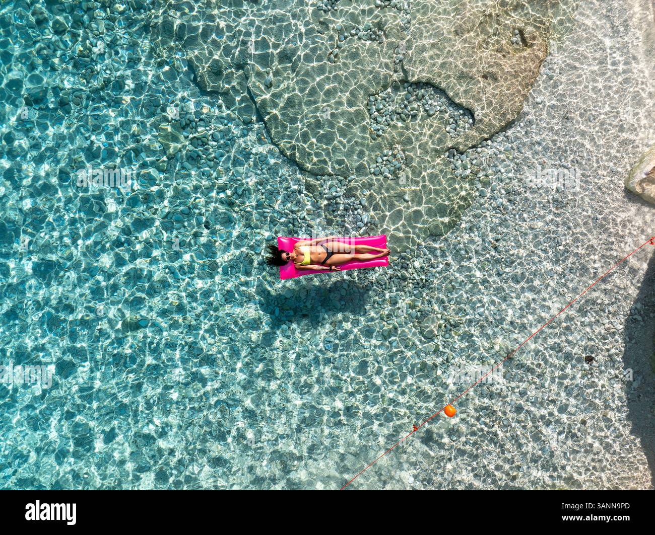 Vue aérienne de la plage de mariolu avec une femme sur un matelas gonflable en eau turquoise cristalline, Baunei, Italie. Banque D'Images