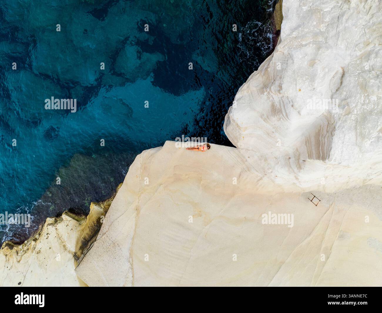 Vue aérienne des falaises escarpées et des rochers blancs par l'océan bleu tranquille, Triovassalos, Grèce. Banque D'Images