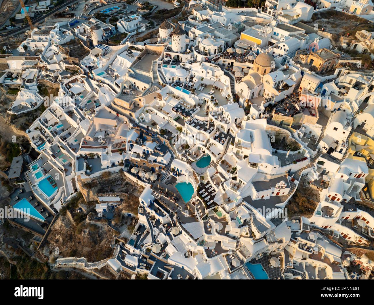 Vue aérienne des bâtiments blancs pittoresques et des piscines sous un ciel ensoleillé, Oia, Santorin, Grèce. Banque D'Images