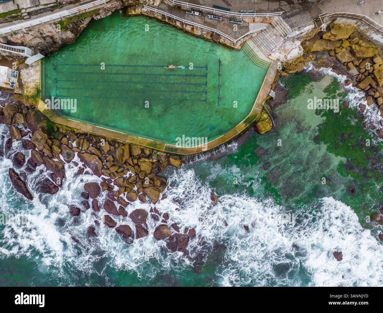Vue aérienne d'une personne nageant à Bronte Baths, une piscine d'eau salée au bord de l'océan, Sydney, Nouvelle-Galles du Sud, Australie. Banque D'Images