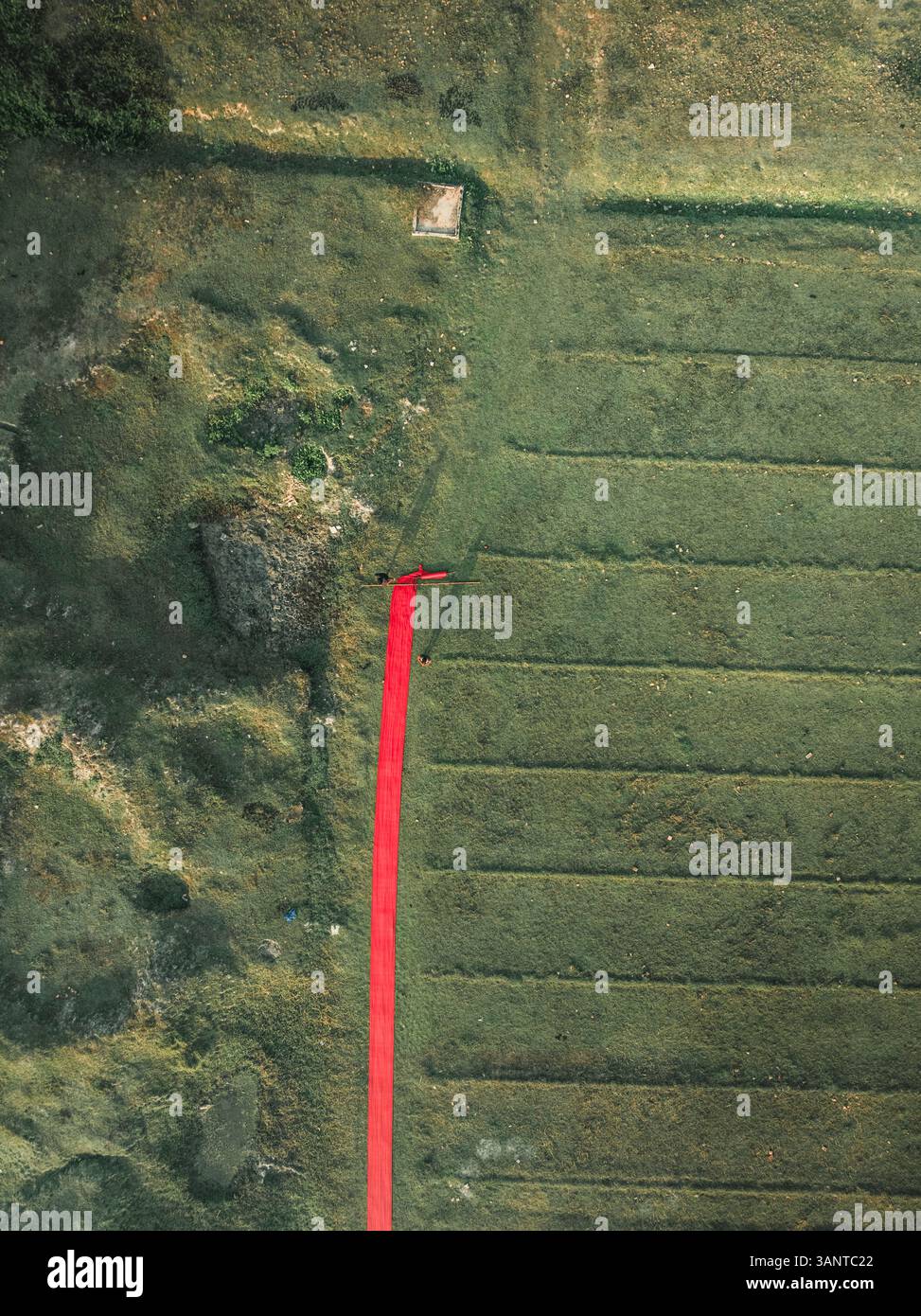 Vue aérienne de personnes séchant des tissus dans une usine de tissus entourée de champs verts, Paikar Char, Narsingdi, Dhaka, Bangladesh. Banque D'Images