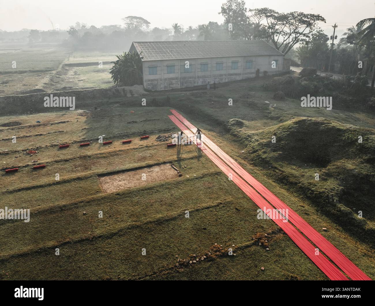 Vue aérienne d'une usine de tissu avec des gens séchant des tissus dans un paysage rural, Paikar Char, Narsingdi, Dhaka, Bangladesh. Banque D'Images