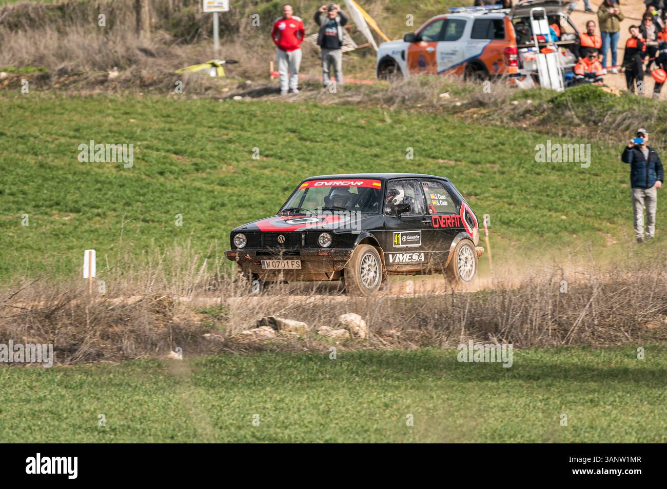 Madrid, Espagne ; 02-15-2025 : une Volkswagen Golf GTI noire traverse une étape de rallye, palpitant les spectateurs le long du chemin de terre. Le design rétro de la voiture Banque D'Images