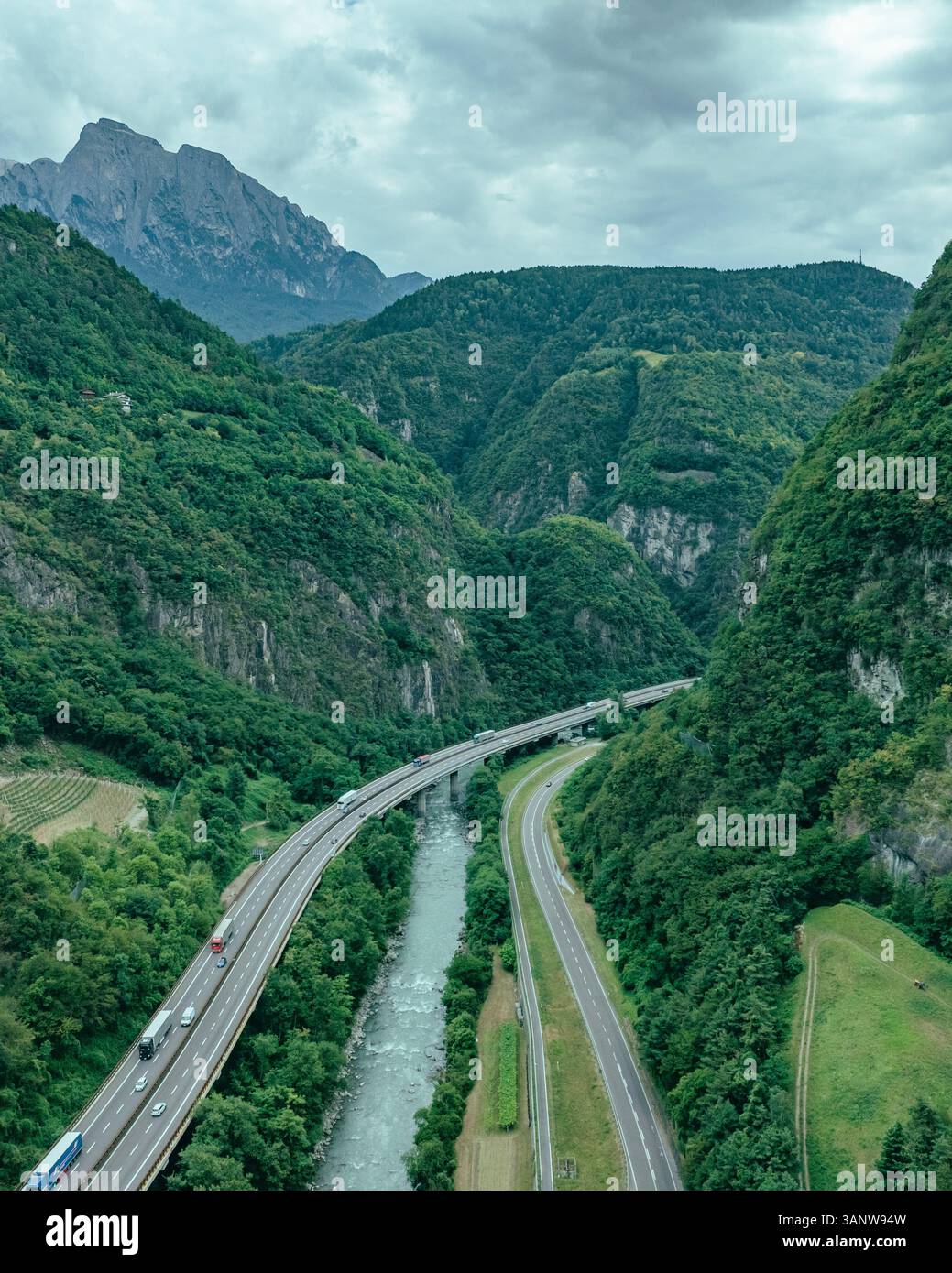 Vue aérienne des montagnes majestueuses et de la vallée luxuriante avec route sinueuse et rivière, Ritten, Italie. Banque D'Images