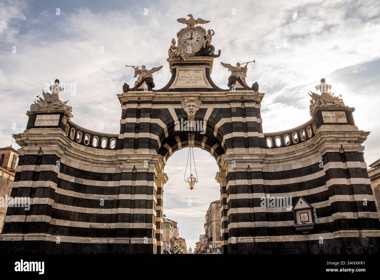 Arche baroque monumentale Porta Garibaldi à Catane, Sicile, avec des rayures de pierre de lave noires et blanches sous un ciel nuageux. Monument architectural bu Banque D'Images