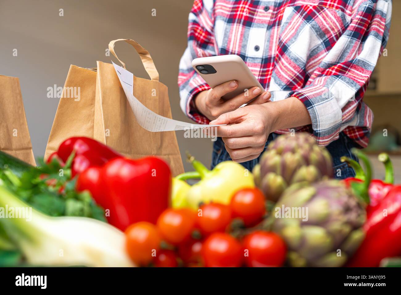 Femme scannant le code QR sur le reçu d'épicerie avec smartphone Banque D'Images