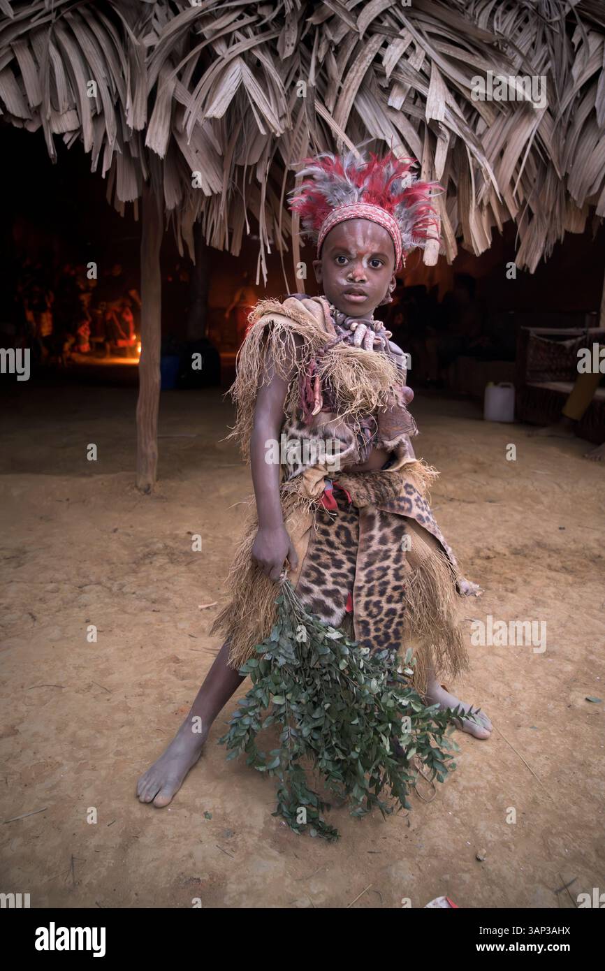 Portrait d'un garçon devant un temple, vêtu d'un costume rituel fait de peaux d'animaux et de plumes, un matin après un Bwiti toute nuit. Banque D'Images