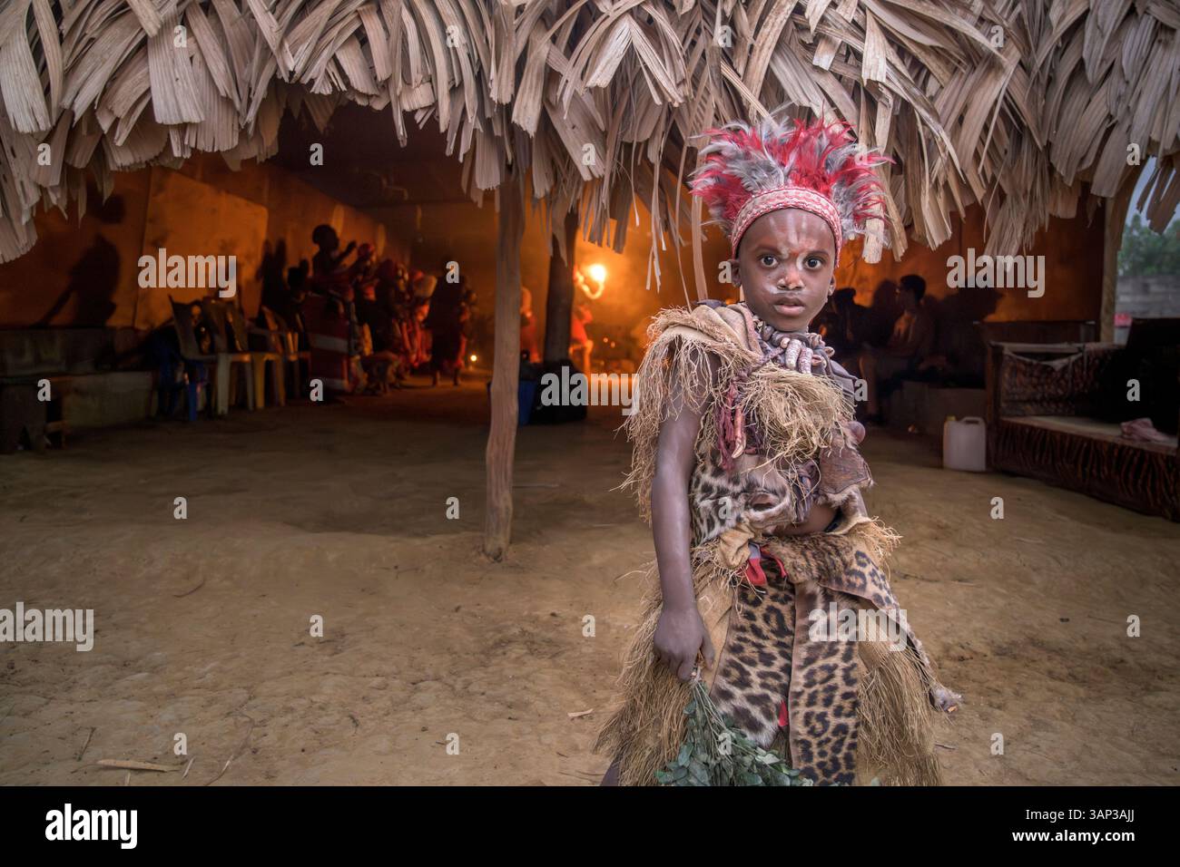 Portrait d'un garçon devant un temple, vêtu d'un costume rituel fait de peaux d'animaux et de plumes, un matin après un Bwiti toute nuit. Banque D'Images