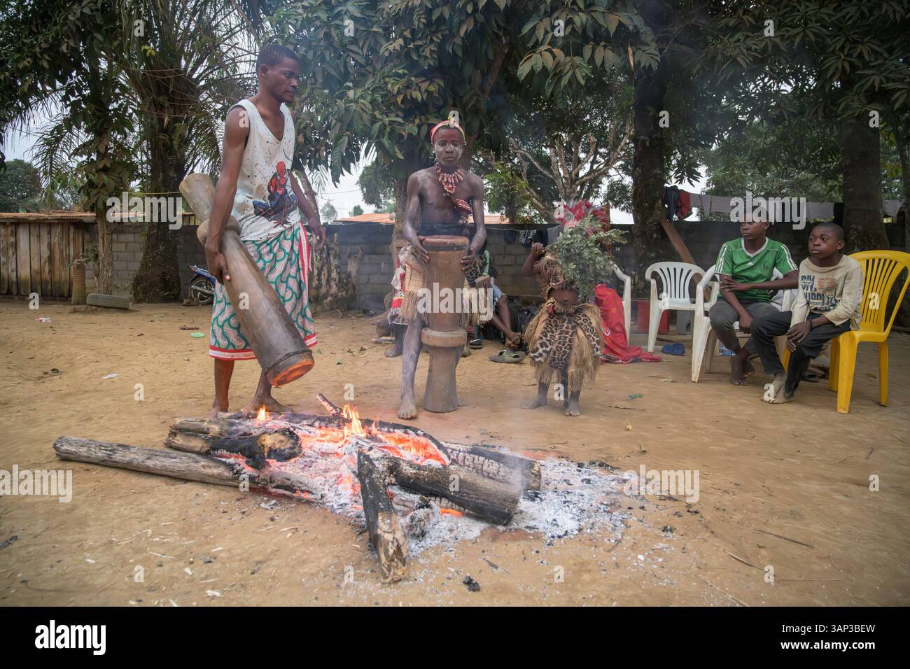 Les participants à une cérémonie Bwiti réchauffent des tambours près du feu pour améliorer leur son. Banque D'Images