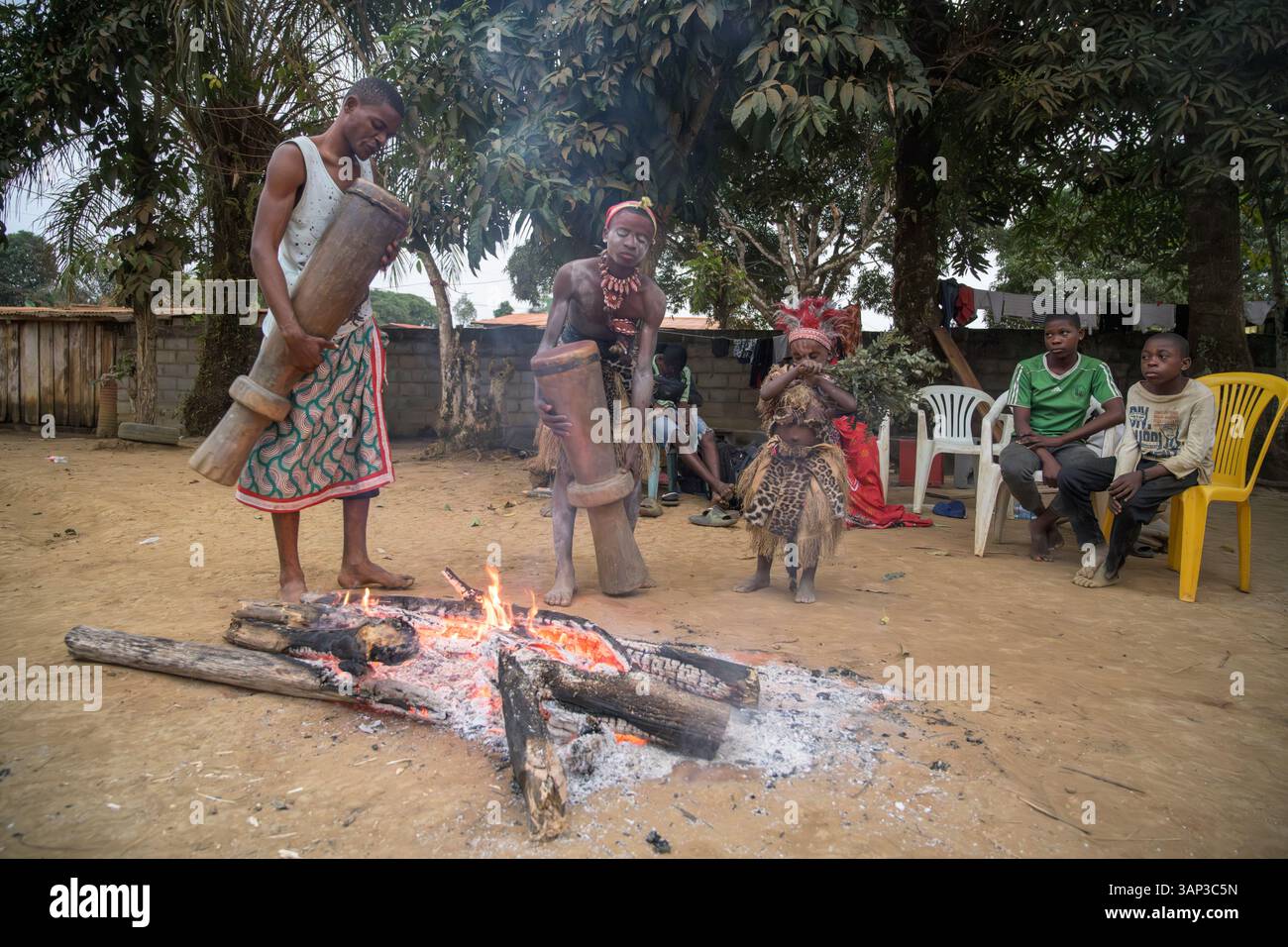 Les participants à une cérémonie Bwiti réchauffent des tambours près du feu pour améliorer leur son. Banque D'Images