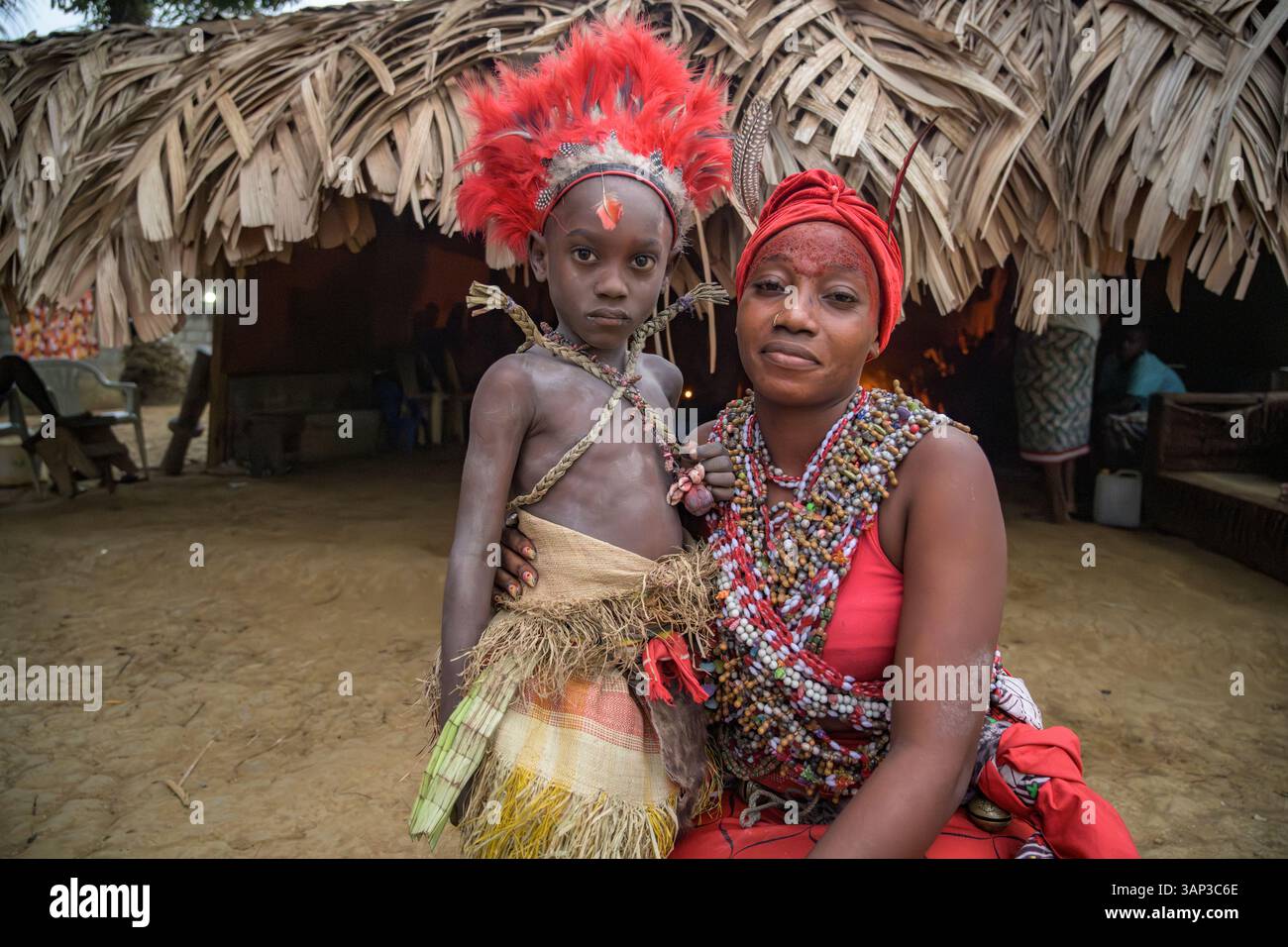 Portrait d’une mère et de son garçon devant un temple, vêtus d’un costume rituel fait de peaux d’animaux et de plumes, un matin après un Bwiti. Banque D'Images
