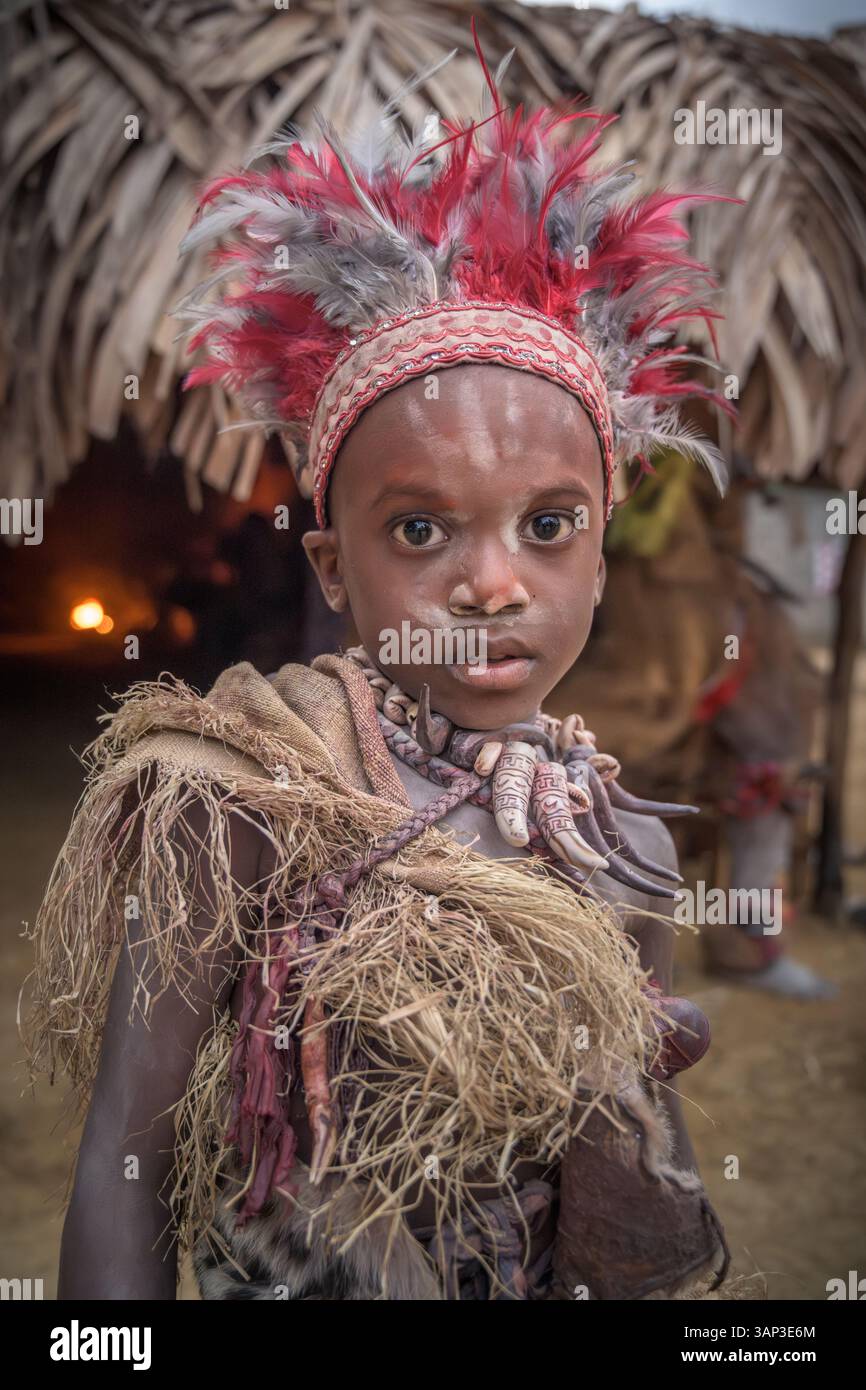Portrait d'un garçon devant un temple, vêtu d'un costume rituel fait de peaux d'animaux et de plumes, un matin après une cérémonie toute la nuit. Banque D'Images