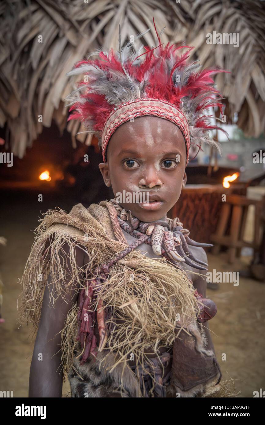 Portrait d'un garçon devant un temple, vêtu d'un costume rituel fait de peaux d'animaux et de plumes, un matin après une cérémonie toute la nuit. Banque D'Images