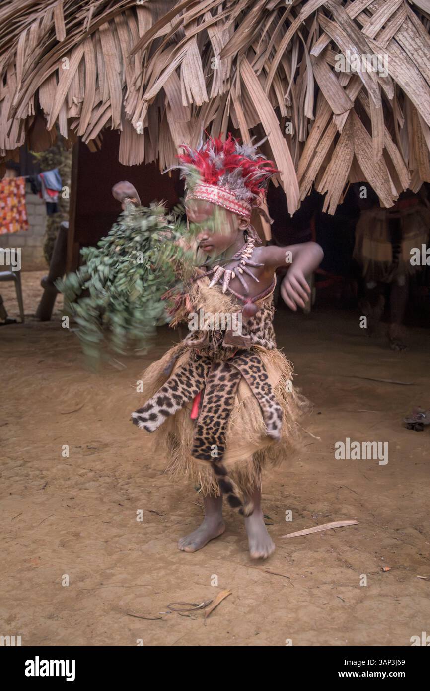 Portrait d'un garçon devant un temple, vêtu d'un costume rituel fait de peaux d'animaux et de plumes, un matin après une cérémonie toute la nuit. Banque D'Images