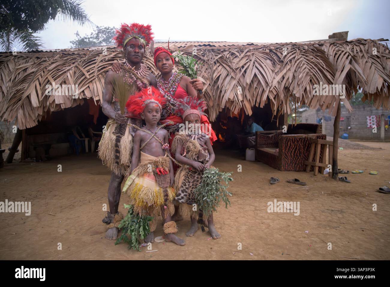 Portrait d’une famille devant un temple, vêtue d’un costume rituel fait de peaux d’animaux et de plumes, un matin après une cérémonie toute la nuit. Banque D'Images