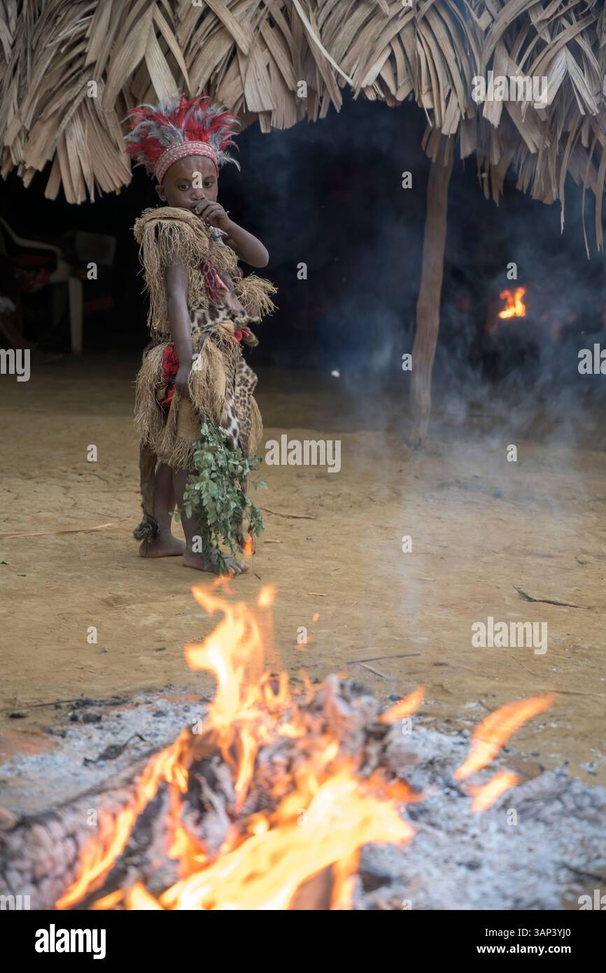 Portrait d'un garçon devant un temple, vêtu d'un costume rituel fait de peaux d'animaux et de plumes, un matin après une cérémonie toute la nuit. Banque D'Images