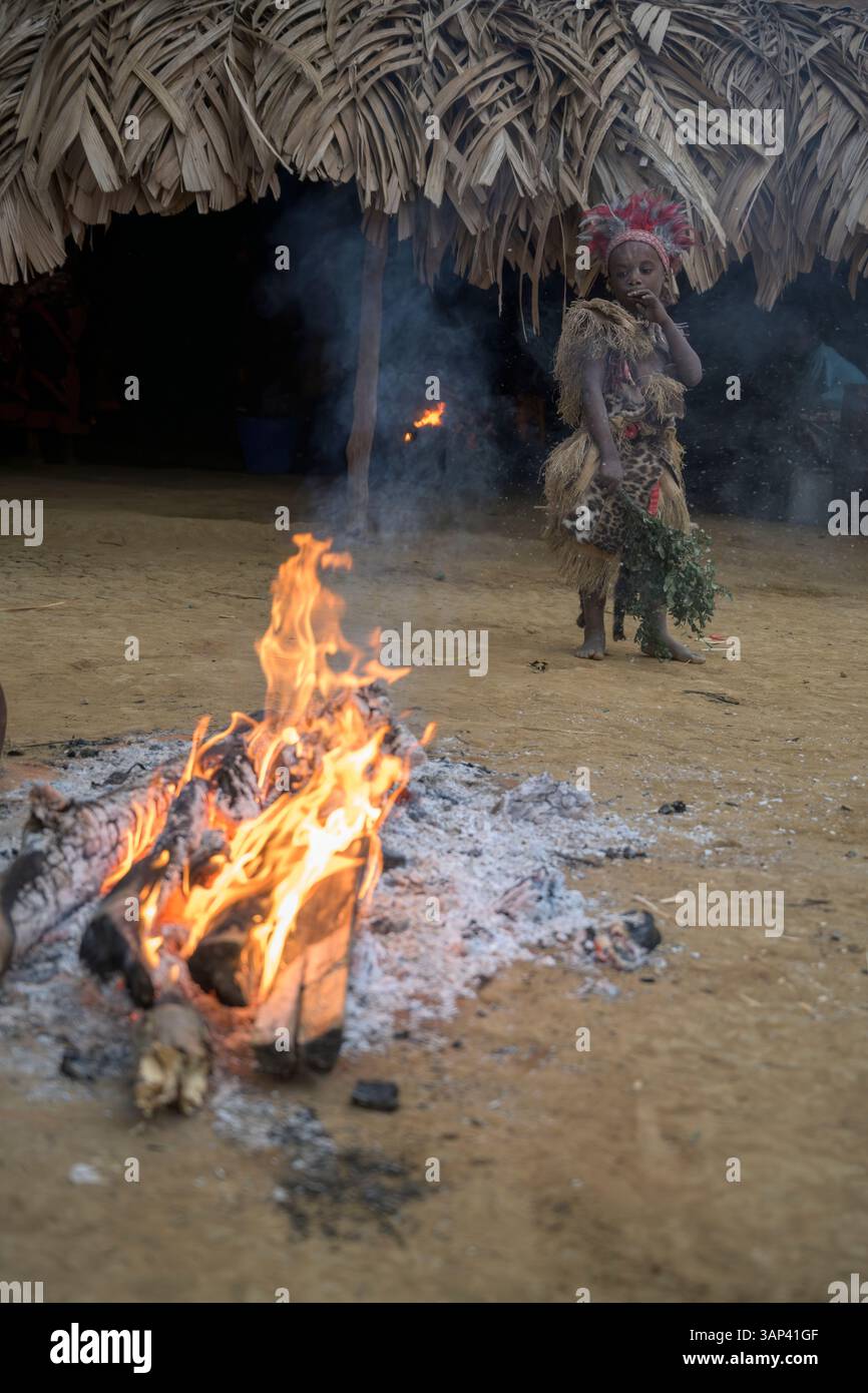 Portrait d'un garçon devant un temple, vêtu d'un costume rituel fait de peaux d'animaux et de plumes, un matin après une cérémonie toute la nuit. Banque D'Images