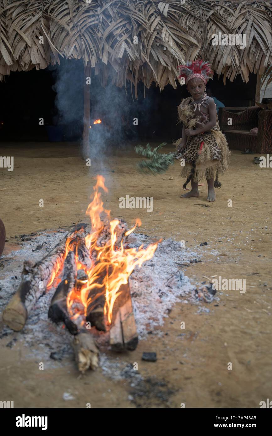 Portrait d'un garçon devant un temple, vêtu d'un costume rituel fait de peaux d'animaux et de plumes, un matin après une cérémonie toute la nuit. Banque D'Images