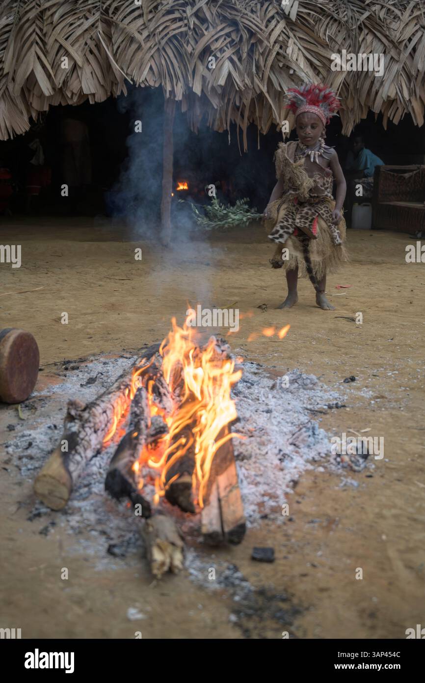 Portrait d'un garçon devant un temple, vêtu d'un costume rituel fait de peaux d'animaux et de plumes, un matin après une cérémonie toute la nuit. Banque D'Images