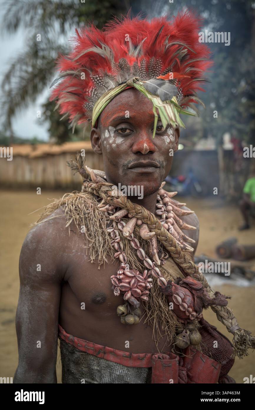 Portrait d'un garçon devant un temple, vêtu d'un costume rituel fait de peaux d'animaux et de plumes, un matin après une cérémonie toute la nuit. Banque D'Images