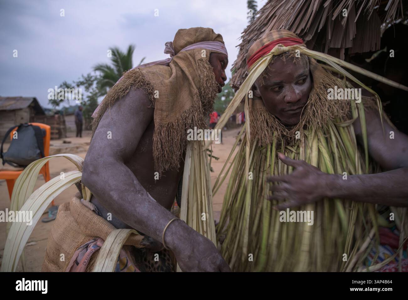Participants à une cérémonie Bwiti, vêtus d'une tenue rituelle faite de feuilles de palmier séchées, après une séance toute la nuit. Banque D'Images